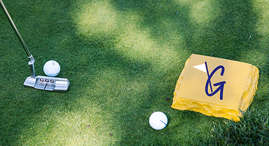 Golf club hitting ball on course with inset Guild for Good icon