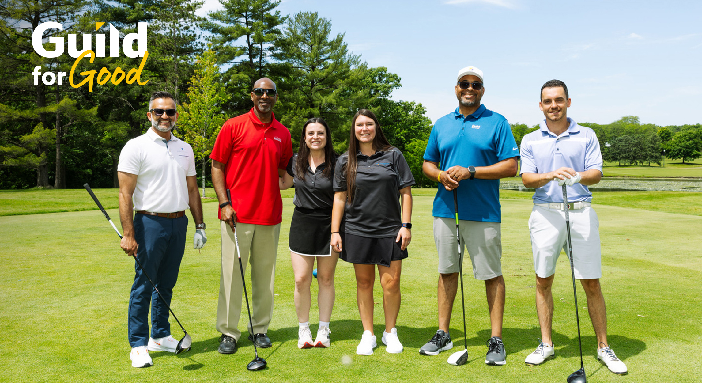 Guild Giving golf event participants pose together on a sunny golf course before play
